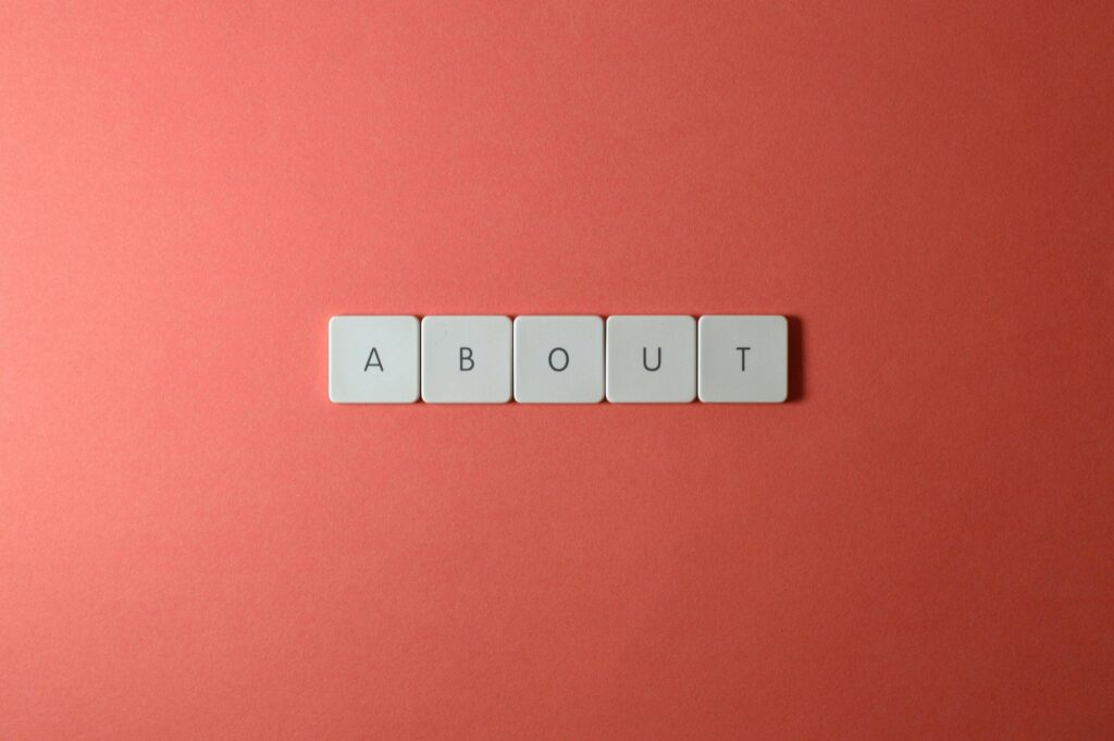 Close-up of keyboard buttons spelling 'ABOUT' against a red surface, minimalist style.